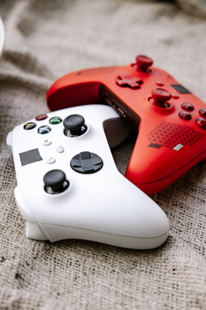 Close-up view of red and white Xbox wireless controllers placed on textile fabric.